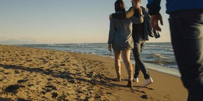 Group of friends having fun on beach during autumn day photo