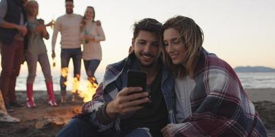 Couple enjoying bonfire with friends on beach photo