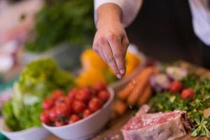 Chef putting salt on juicy slice of raw steak photo