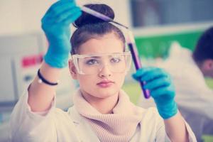 female student with protective glasses making chemistry experiment photo