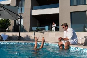 familia feliz disfruta de vacaciones en una casa de lujo con piscina. la pareja mayor pasa tiempo con su hijo durante las vacaciones. enfoque selectivo foto