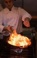 chef haciendo flambeado en la comida foto