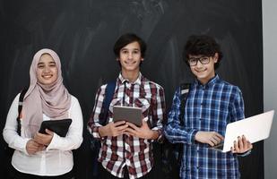 grupo de adolescentes árabes que trabajan en computadoras portátiles y tabletas foto