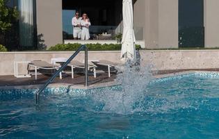 Happy family enjoys vacation in a luxury house with pool. Senior couple spends time with their son during the vacation. Selective focus photo