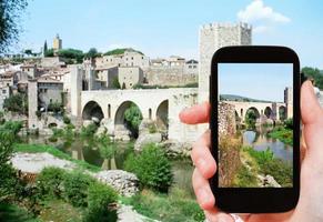 tourist shoots photo of bridge in Besalu town