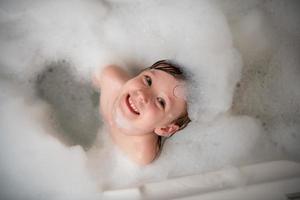 top view of little girl in bath playing with foam photo