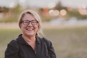 Portrait of an elderly woman with blonde hair and glasses on the beaches of the Mediterranean Sea at sunset. Selective focus photo