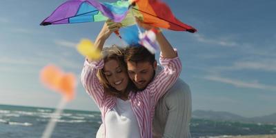 Happy couple having fun with kite on beach photo