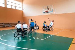 veteranos de guerra discapacitados equipos mixtos de baloncesto de raza y edad en sillas de ruedas jugando un partido de entrenamiento en un gimnasio deportivo. concepto de rehabilitación e inclusión de personas con discapacidad foto