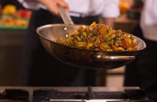 chef flipping vegetables in wok photo