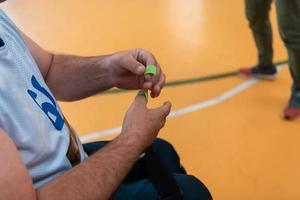 un jugador de baloncesto discapacitado se pone un corsé y se venda los brazos y los dedos para prepararse para un partido en la arena foto