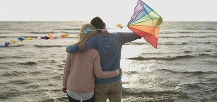 Happy couple having fun with kite on beach photo