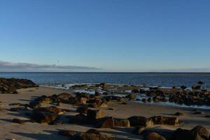 Vast open ocean with large brown rocks on the shore photo