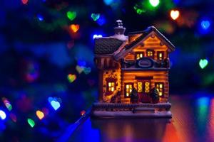 christmas house figure on table on multicolor blurred heart bokeh background photo