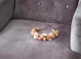 pink and beige floral headband laying on grey velour chair background photo