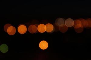 Round orange bokeh lights on black background. Defocused city lights photo