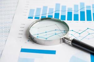 Magnifying glass on chart graph spreadsheet paper. Financial development, Banking Account, Statistics, economy, Stock exchange trading, Business office company meeting concept. photo