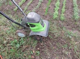 KYIV OBLAST, UKRAINE - OCTOBER 02, 2022 Cultivation of beds with a manual electric cultivator photo