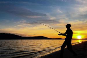 Young man fishing at sunset photo