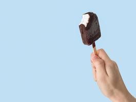 Teen-ager holding eskimo ice cream on light blue background. photo