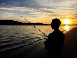 joven pescando al atardecer foto