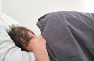 Man sleeping in bed under blanket in the morning. photo