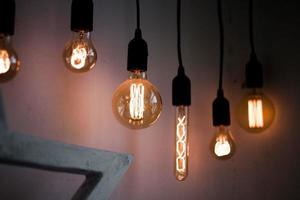 Hanging edison light bulbs on black strings. Glowing vintage electric bulbs photo