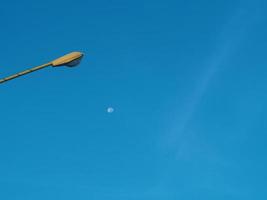 The street light tower on the background is blue sky And there is a small moon in the middle photo