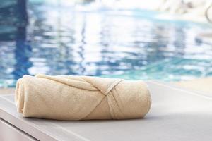 Folded towels are placed on a chair next to the swimming pool. photo