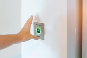 Hand open the door by No touch sensor switch on the wall at office or apartment. Contactless, modern, Technology and safety concept photo
