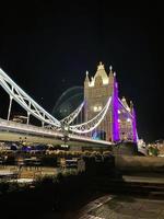 A view of Tower Bridge in London at night lit up in purple photo