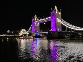 A view of Tower Bridge in London at night lit up in purple photo