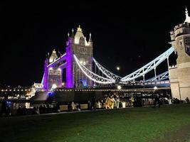 una vista del puente de la torre en londres en la noche iluminada en púrpura foto