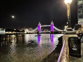 una vista del puente de la torre en londres en la noche iluminada en púrpura foto