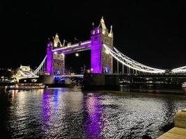 A view of Tower Bridge in London at night lit up in purple photo