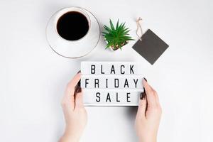 Black friday sale concept. Woman holds in her hands lightbox with text on white background. photo