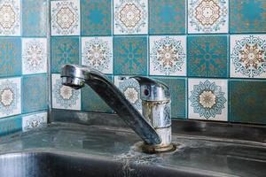 Old rusty sink faucet in kitchen. Rust streaks, calcium scale, hard water. photo