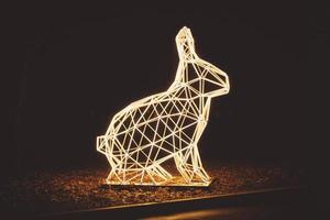 Light sculpture in city park, bunny made of lamp tubes, night view photo