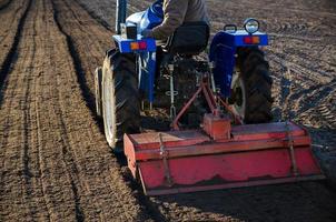 A farmer on a tractor cultivates a farm field. Softening the soil and preparing for cutting rows for the next sowing season in the spring. Land cultivation. Farm business. Work in agricultural photo