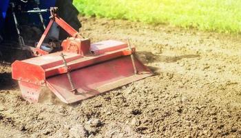 Tractor with milling machine loosens, grinds and mixes ground. Field preparation for new crop planting. Cultivation equipment. Grinding and loosening soil, removing plants and roots from past harvest. photo