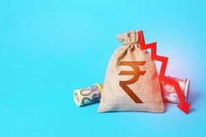 Indian rupee money bag and arrow down. Falling economy. Drop in profits. Decrease in interest rate deposit rate. Low income, economic difficulties. Unprofitability, recession and depression. Inflation photo