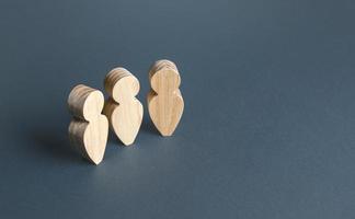 Three wooden human figurines on a gray background. Communication and discussion. Social Meeting. Assistance, cooperation and collaboration. photo