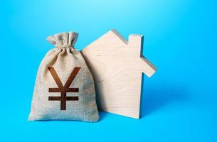 House silhouette and a chinese yuan or japanese yen symbol money bag. Purchase, investment in real estate construction. Mortgage. Realtor services. House project. Rental business. Property appraisal. photo