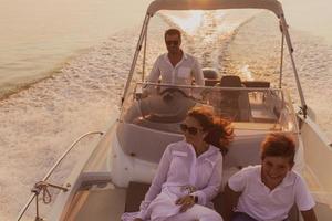 A senior couple in casual outfits with their son enjoy while riding a boat at sea at sunset. The concept of a happy family. Selective focus photo