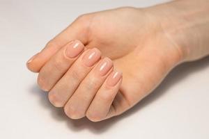 Nail care and manicure. Close-up of a beautiful female hand with nude gel polish on nails. Natural square nails. A high resolution photo