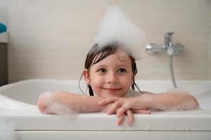 little girl in bath playing with foam photo
