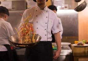 chef volteando verduras en wok foto