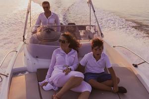 una pareja mayor con ropa informal con su hijo disfruta mientras viaja en un bote en el mar al atardecer. el concepto de una familia feliz. enfoque selectivo foto