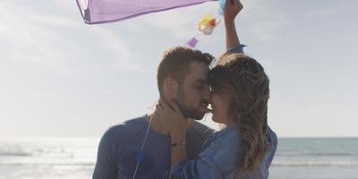 Happy couple having fun with kite on beach photo