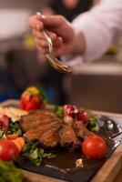 Chef finishing steak meat plate photo